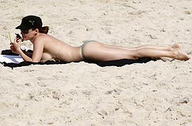 Livre do sutiã, atriz curte seu topless e pega sol
