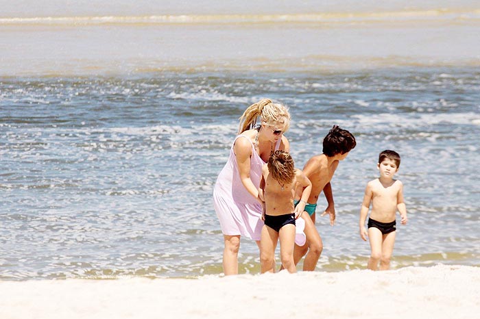 Cuidadosa, ela faz os filhos se refrescarem o tempo todo na praia