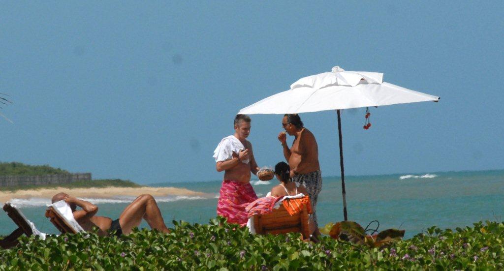 Galvão Bueno, com um grupo de amigos, comendo um petisco na beira da praia