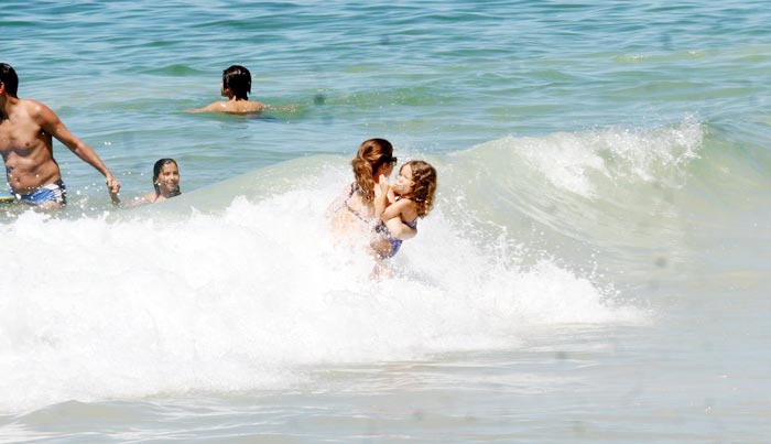 Cláudia Abreu curte praia acompanhada da família