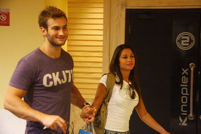 O casal segue pelo corredor do shopping com bolsas de compras