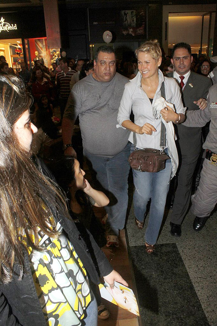 Xuxa é amparada pelos seguranças ao sair ao shopping