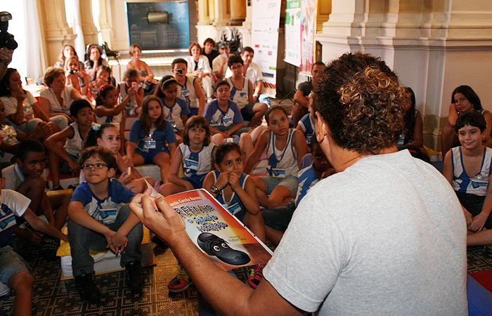 Cercado de crianças, David Brazil lê livro infantil