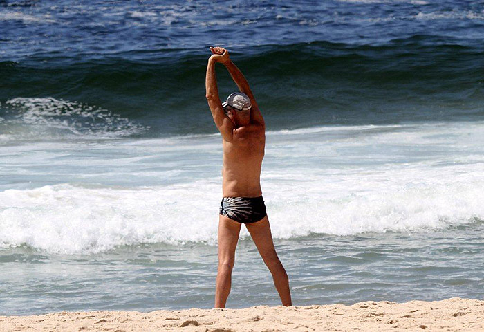 Enquanto se exercita, Marcos Caruso retira lixo da praia