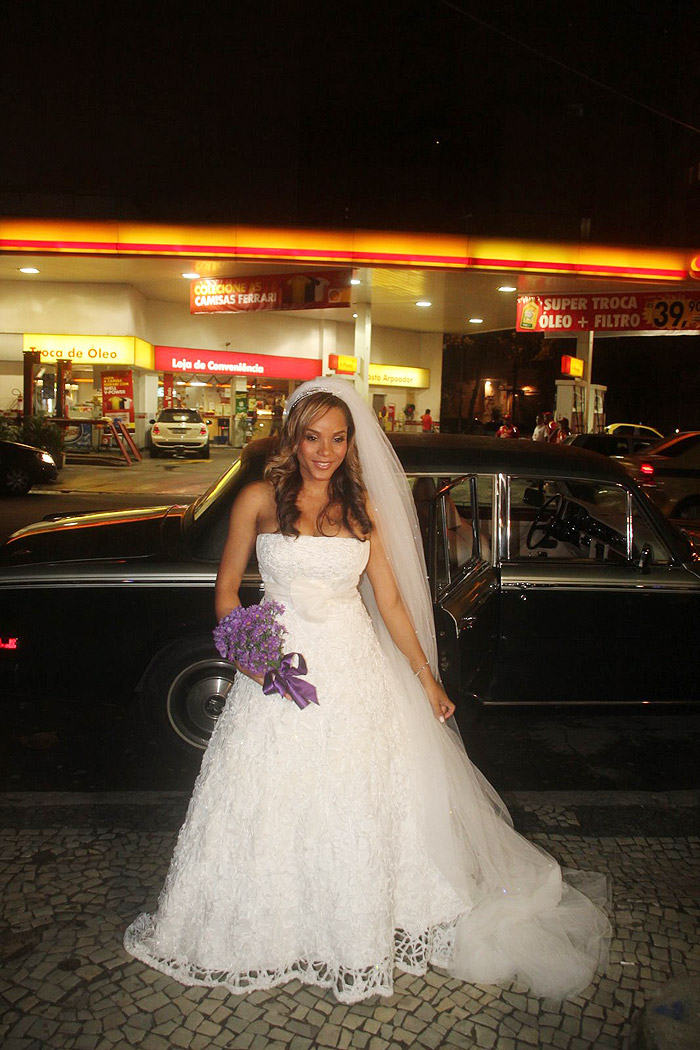 A noiva desce do carro, linda com um vestido tomara que caia e buquê violeta 