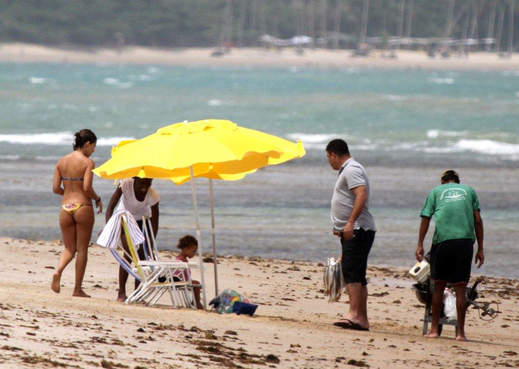 Enquanto segurava os peixes, a mulher Bia aproveitava o sol observando a filha e a babá