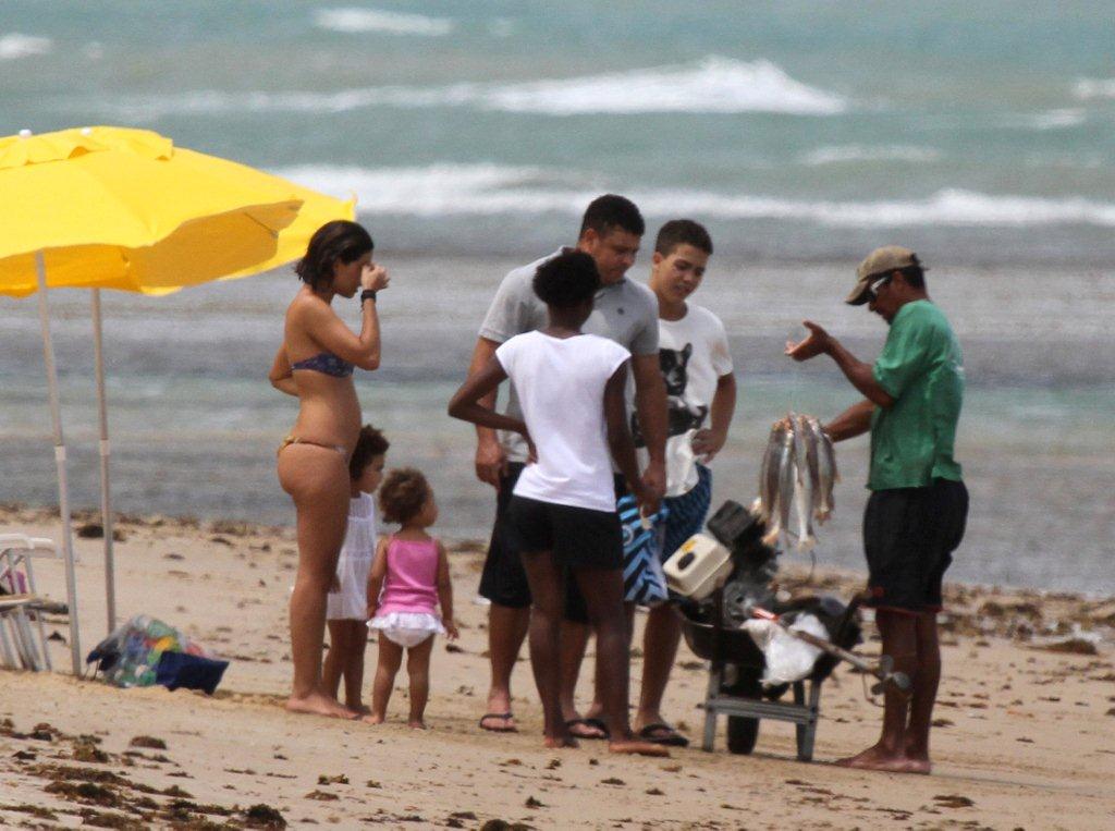 Filhos e esposa do ex-craque observam os peixes oferecidos pelo pescador em Trancoso