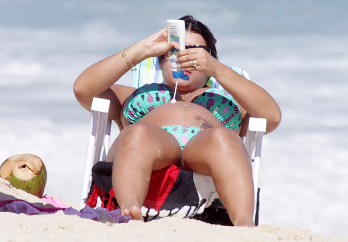 Gravidíssima, Priscila Pires não economiza no protetor solar na praia