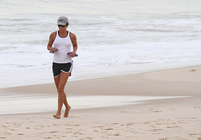 Andrea Beltrão corre pela praia em dia nublado