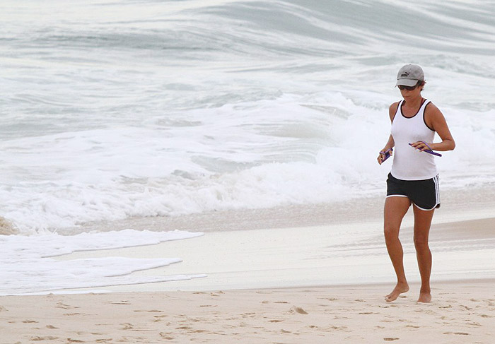 Andrea Beltrão corre pela praia em dia nublado