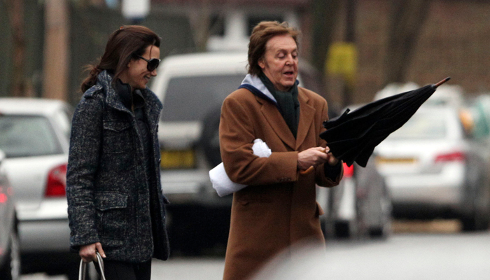 Paul McCartney e Nancy Shevell se divertem tomando chuva, em Londres.