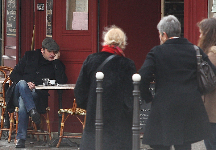 Jean Dujardin cochila em café de Paris enquanto espera pela festa do Oscar
