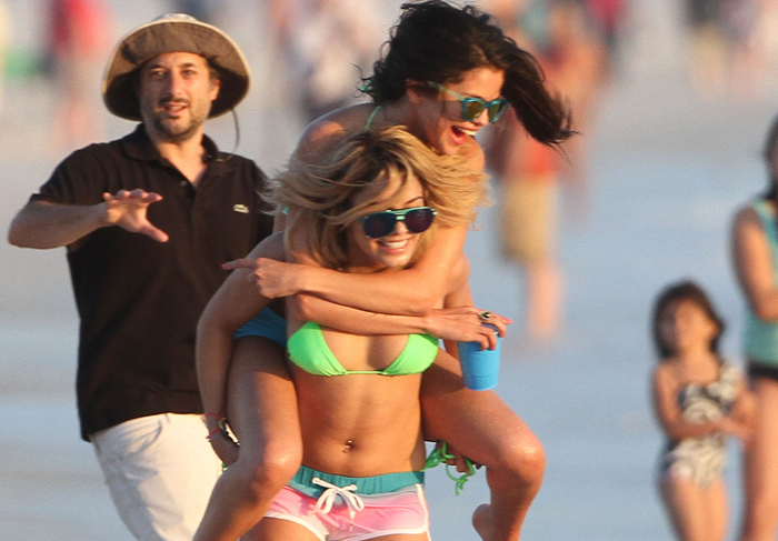 Vanessa Hudgens carrega Selena Gomez nas costas, em praia da Flórida