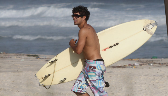 Caio Castro curte praia bem acompanhado