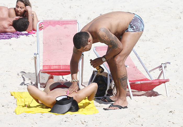  MC Naldo passa bronzeador em Mulher Moranguinho na praia