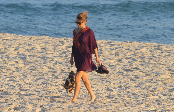 Sozinha e de roupa, Christine Fernandes caminha pela areia na Barra da Tijuca