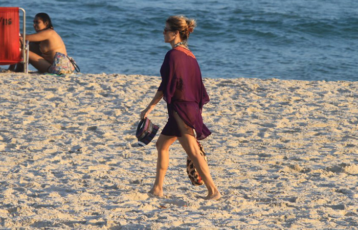 Sozinha e de roupa, Christine Fernandes caminha pela areia na Barra da Tijuca