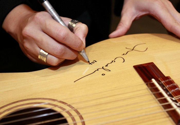 Ana Carolina doa violão autografado para leilão beneficente