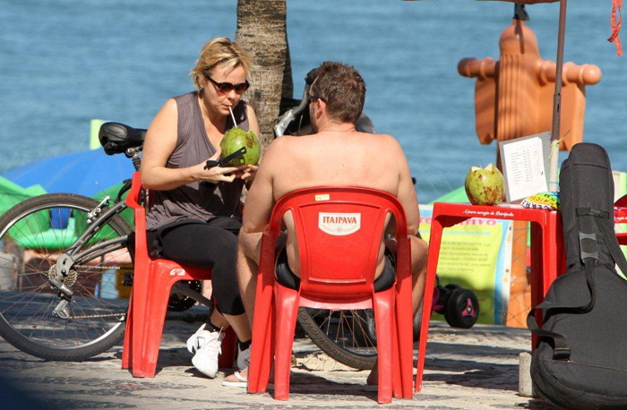 Giulia Gam toma água de coco em praia carioca