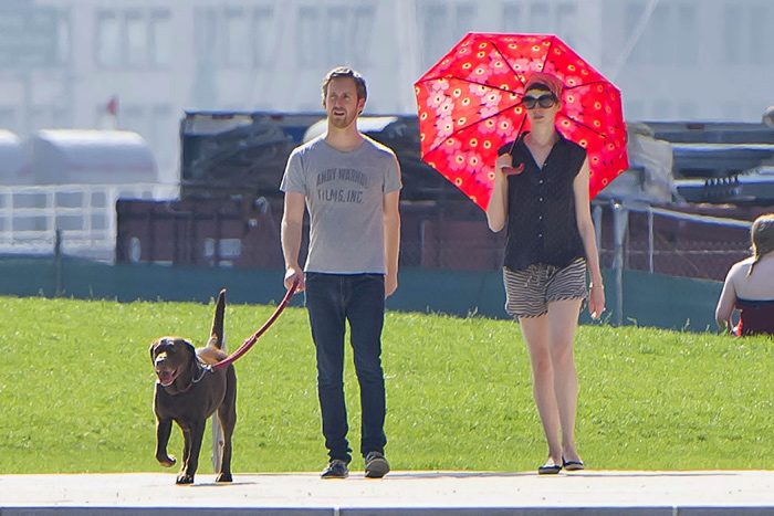 Anne Hathaway se esconde do sol enquanto passeia com seu pet