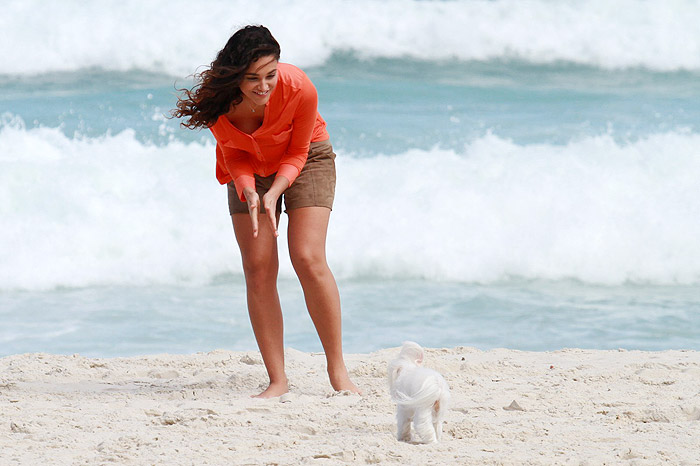 Débora Nascimento recolhe coco de seu cão na areia da praia