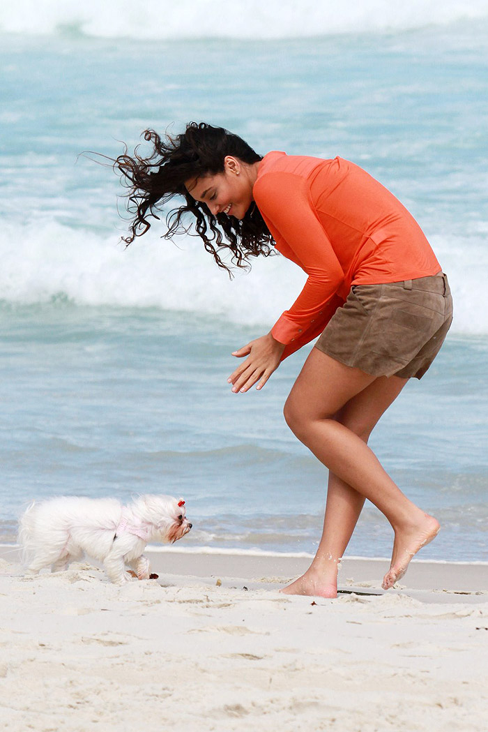 Débora Nascimento recolhe coco de seu cão na areia da praia
