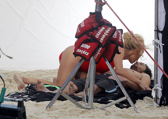 De maiô, Pamela Anderson beija homem durante gravação na praia