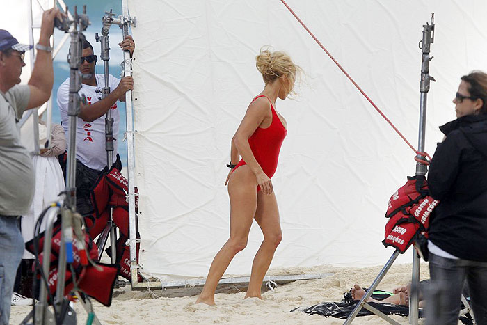 De maiô, Pamela Anderson beija homem durante gravação na praia