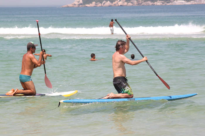Nelson Freitas tenta se equilibrar em cima de prancha na praia