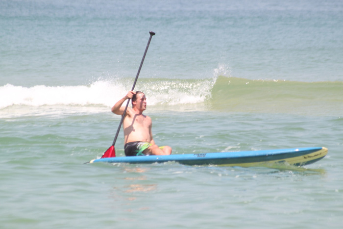 Nelson Freitas tenta se equilibrar em cima de prancha na praia