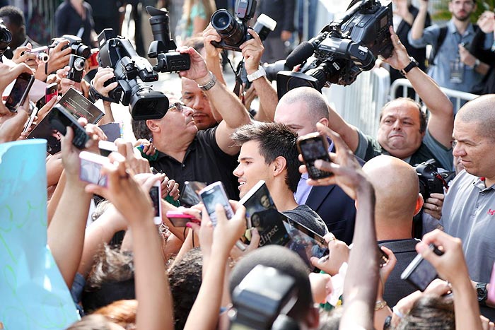 Taylor Lautner distribui autógrafos na porta de hotel, no Rio