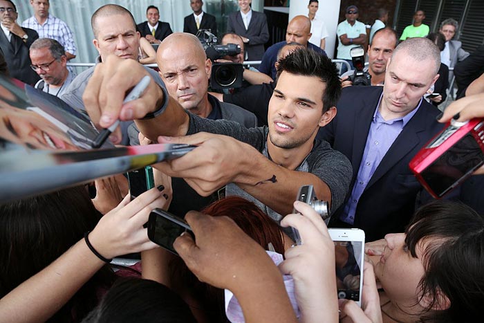 Taylor Lautner distribui autógrafos na porta de hotel, no Rio