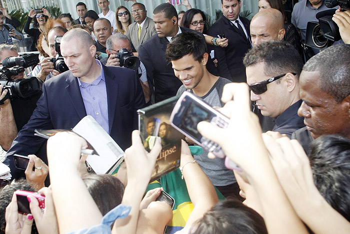 Taylor Lautner distribui autógrafos na porta de hotel, no Rio