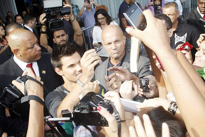 Taylor Lautner distribui autógrafos na porta de hotel, no Rio