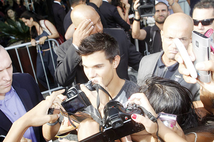 Taylor Lautner distribui autógrafos na porta de hotel, no Rio