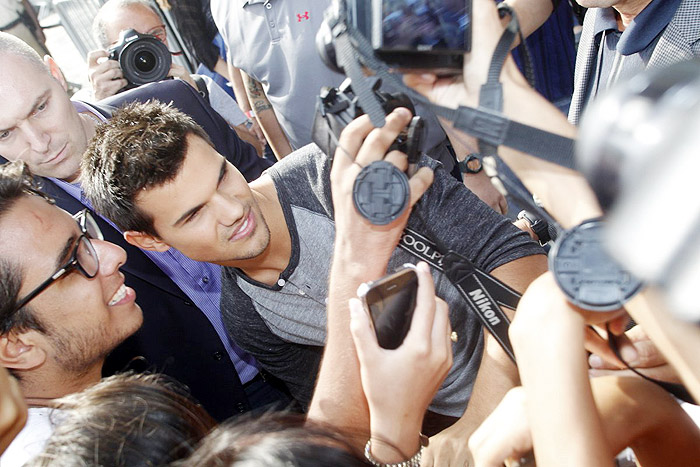 Taylor Lautner distribui autógrafos na porta de hotel, no Rio