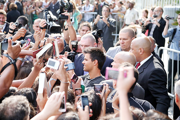 Taylor Lautner distribui autógrafos na porta de hotel, no Rio