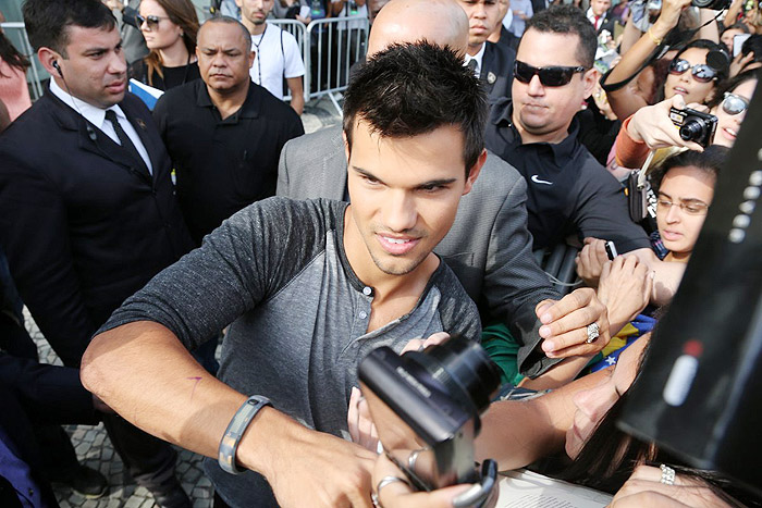 Taylor Lautner distribui autógrafos na porta de hotel, no Rio