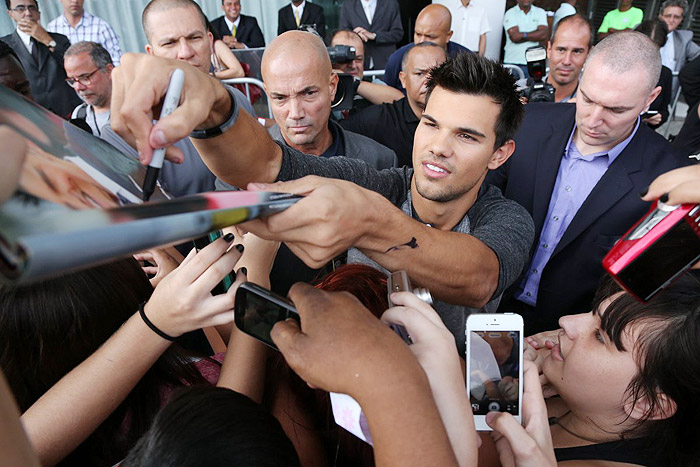 Taylor Lautner distribui autógrafos na porta de hotel, no Rio