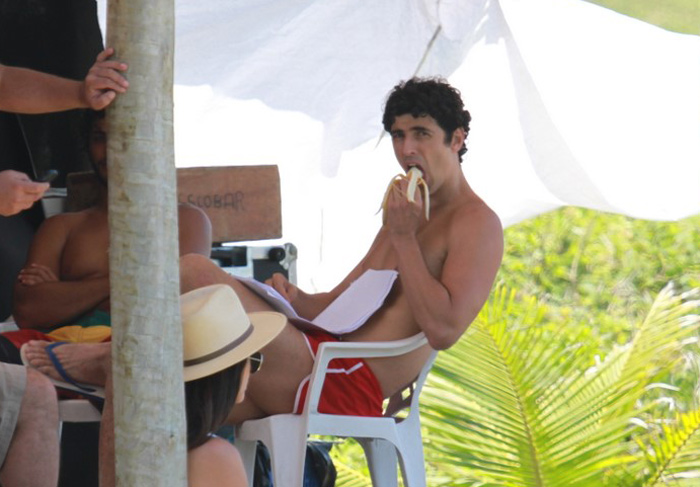 Reynaldo Gianecchini come banana enquanto passa o texto na praia