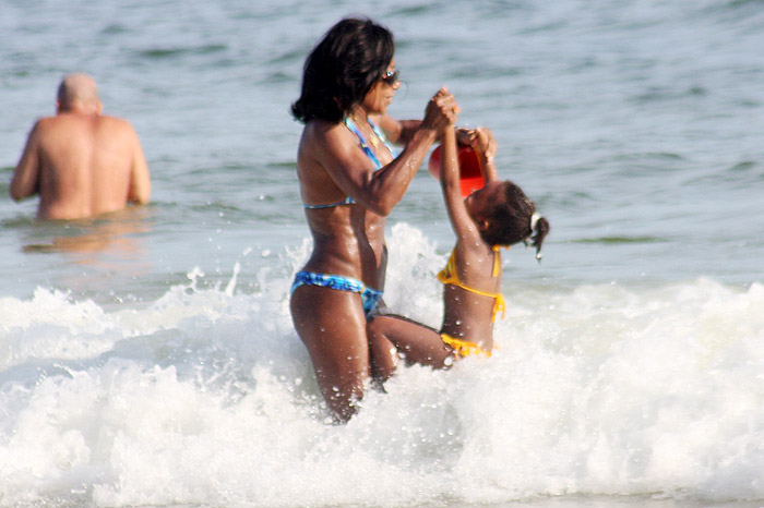 Gloria Maria brinca com sua filha nas ondas
