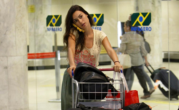Thaila Ayala fala ao telefone e carrega as malas sozinha no aeroporto