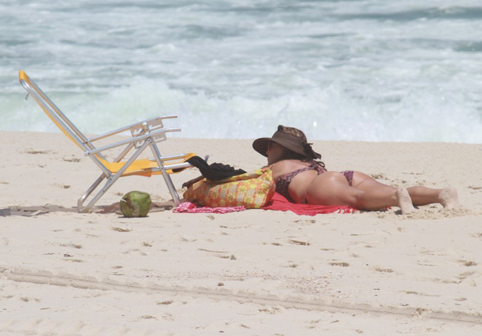 Christine Fernandes lê revista estrangeira na praia