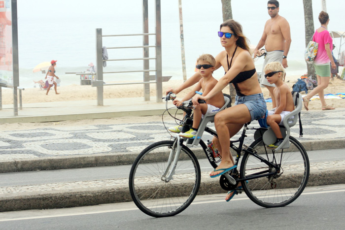 Fernanda Lima pedala com os gêmeos e vê celular ao mesmo tempo 