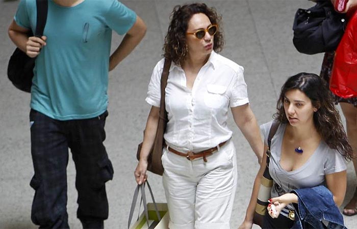 Toda de branco, Eliane Giardini circula pelo aeroporto Santos Dumont