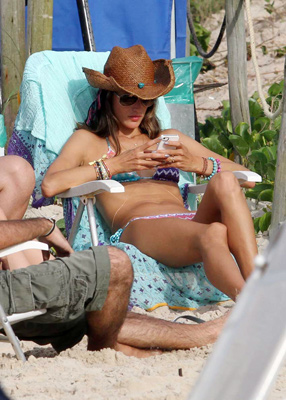Alessandra Ambrósio não larga o celular em dia de praia