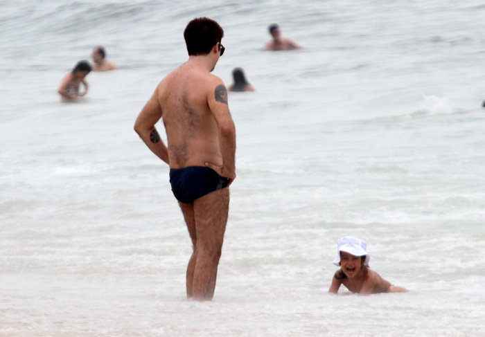  De sunguinha, Rogério Flausino curte praia com a mulher e filha
