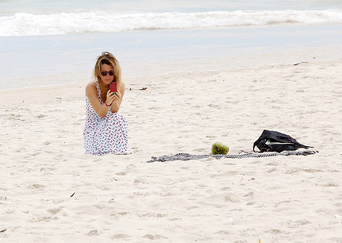 De vestido longo, Juliana Didone relaxa na praia da Barra da Tijuca