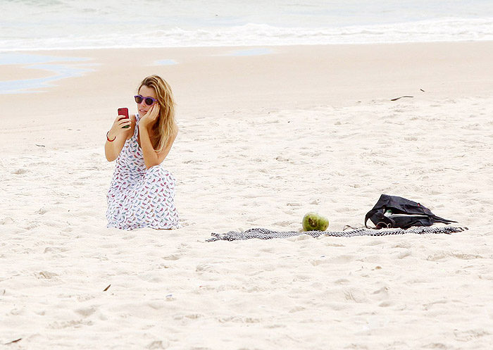 De vestido longo, Juliana Didone relaxa na praia da Barra da Tijuca