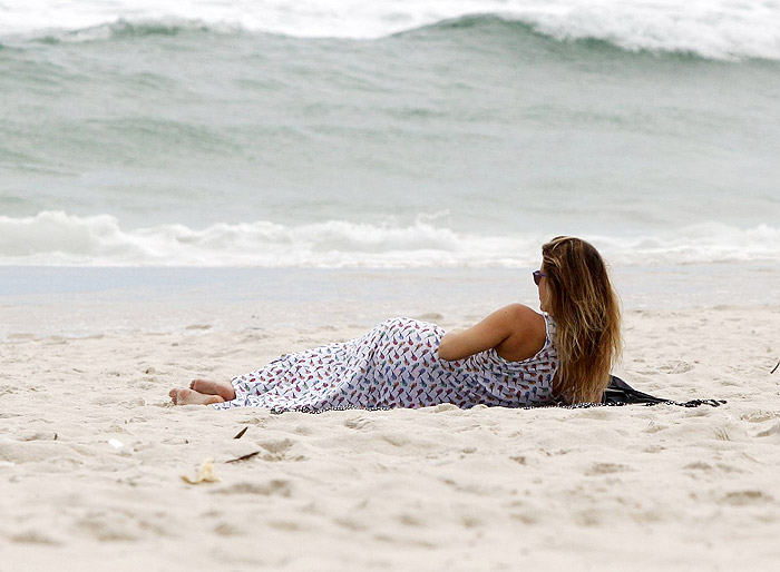 De vestido longo, Juliana Didone relaxa na praia da Barra da Tijuca